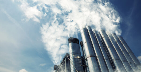 Smoking metal chimneys against blue sky